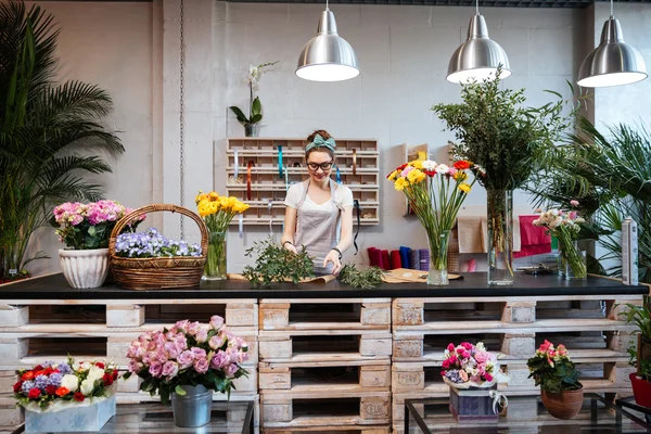 Mujer sonriente florista de pie y trabajando en la florería —  Fotos de Stock
