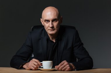 Masada oturan ve kahve içme yakışıklı işadamı