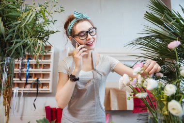 Çiçekçi dükkanı cep telefonuyla konuşan kadın çiçekçi