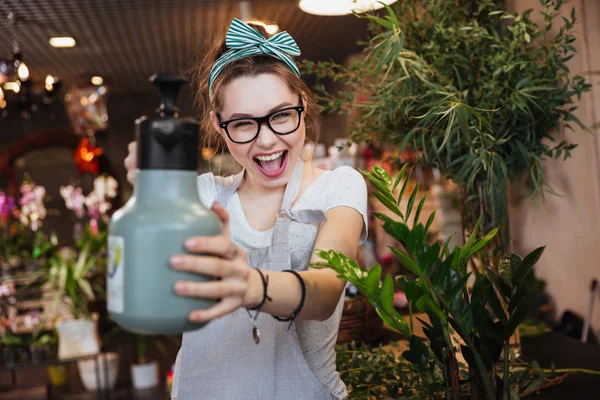 Женщина флорист указывая с водой распылитель на вас — стоковое фото