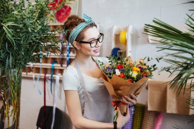 Buket çiçek dükkanında tutan gülümseyen kadın çiçekçi