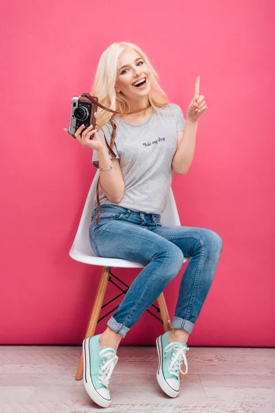 Blonďatá žena sedí na židli s fotoaparátem — Stock fotografie