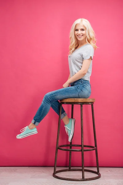 Usměvavá blondýnka sedí na židli — Stock fotografie