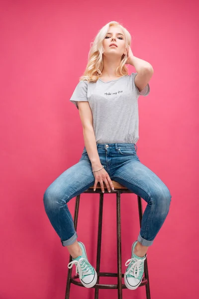 Atraktivní blondýnka pózuje na židli — Stock fotografie