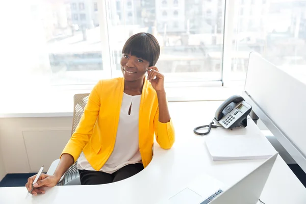 Glimlachende zakenvrouw zittend op haar werkplek op kantoor — Stockfoto