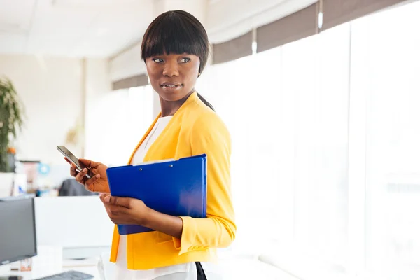 Empresaria afroamericana sosteniendo carpeta y smartphone — Foto de Stock