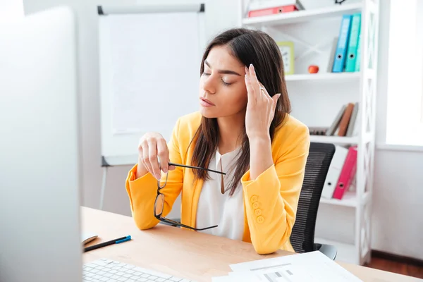 Бізнес-леді сидить з головним болем на своєму робочому місці — стокове фото