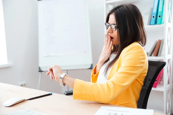 Femme d'affaires à la recherche sur la montre-bracelet au bureau — Photo