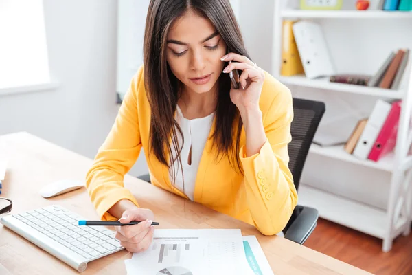 Mulher de negócios falando ao telefone e analisando gráficos — Fotografia de Stock