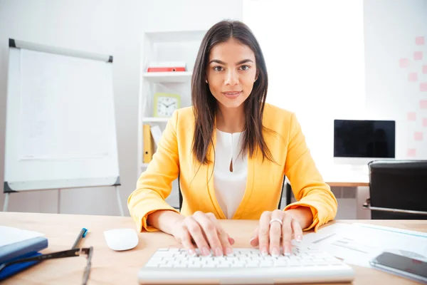 Empresaria encantadora escribiendo en el teclado en la oficina —  Fotos de Stock