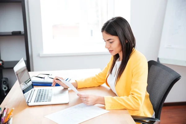 Geschäftsfrau arbeitet mit Papieren und Laptop — Stockfoto