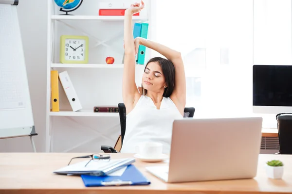 Businesswoman stretching hands in office
