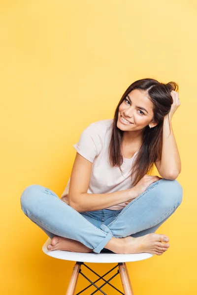 Lycklig kvinna sitter på en stol och tittar på kameran — Stockfoto