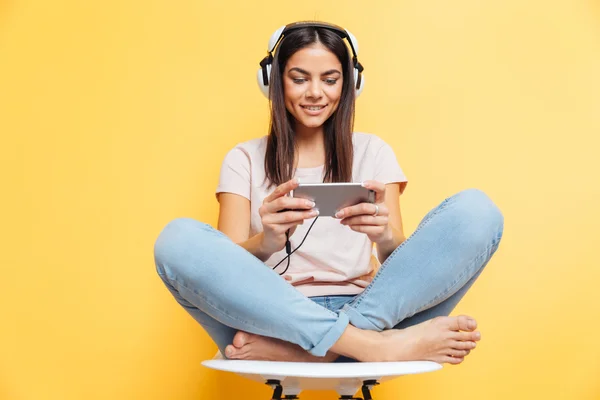 Szczęśliwa kobieta słuchanie muzyki w słuchawkach i korzystanie smartphone — Zdjęcie stockowe
