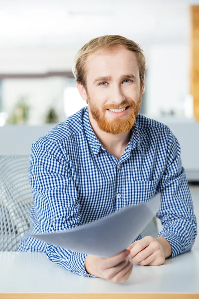Cheerful businessman sitting in office and giving papers to you