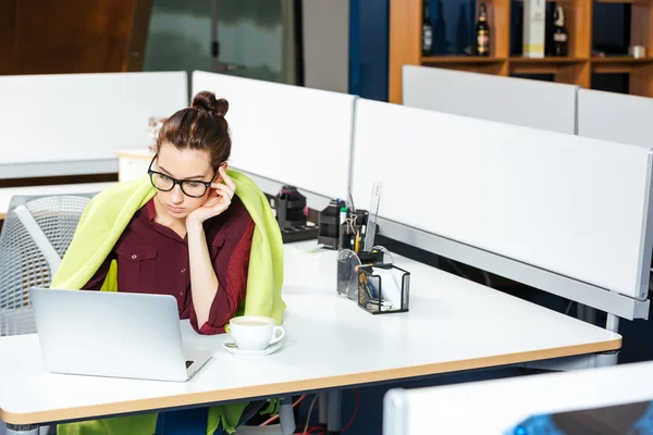 Businesswoman working with laptop and feeling cold in office