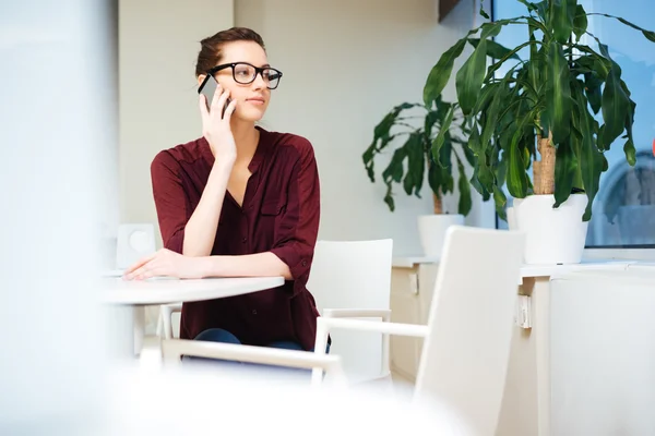 Femme d'affaires pensive dans des lunettes parlant sur un téléphone portable au café — Photo