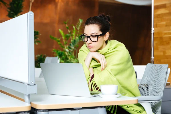 Beautiful thoughtful woman using laptop and feeling cold on workplace — Stock Photo, Image