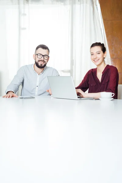 Zwei lächelnde Geschäftsleute, die im Besprechungsraum sitzen und Laptop benutzen — Stockfoto