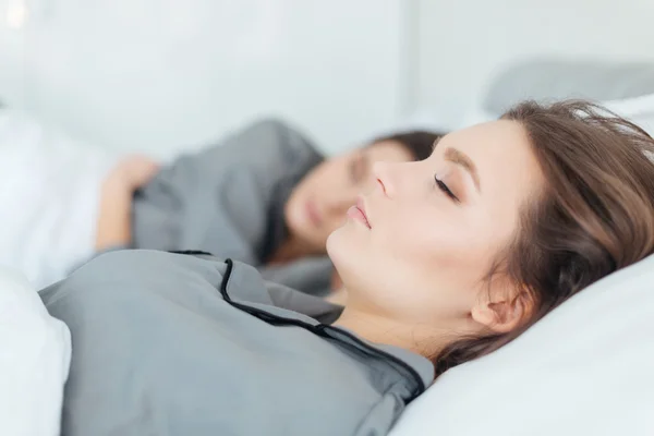 Dos mujeres en pijama gris durmiendo en la cama — Foto de Stock