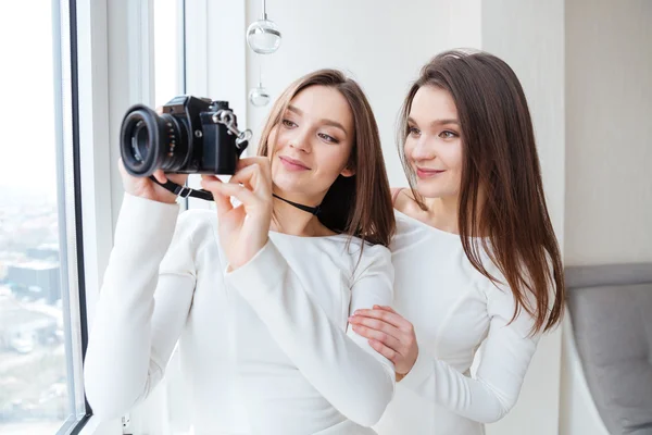 2 人の姉妹は双子の窓の近くにカメラを使用して写真を撮る — ストック写真