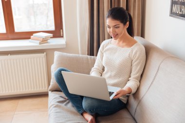 Dizüstü bilgisayar kullanan gülümseyen kadın