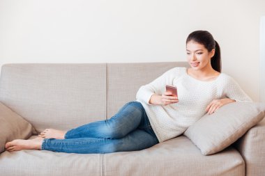 Kanepede yatan ve smartphone kullanarak kadın