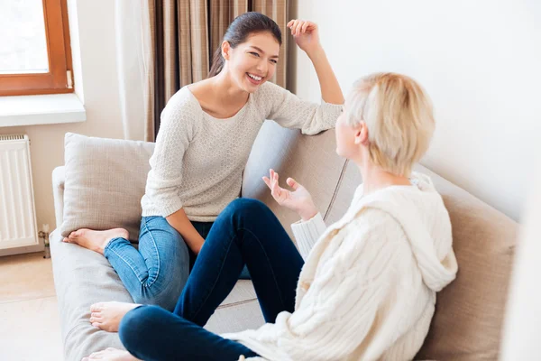 Dos chicas sentadas en el sofá y cotilleando — Foto de Stock