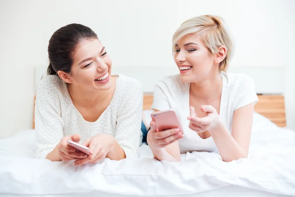 Женщины используют смартфоны на кровати — стоковое фото