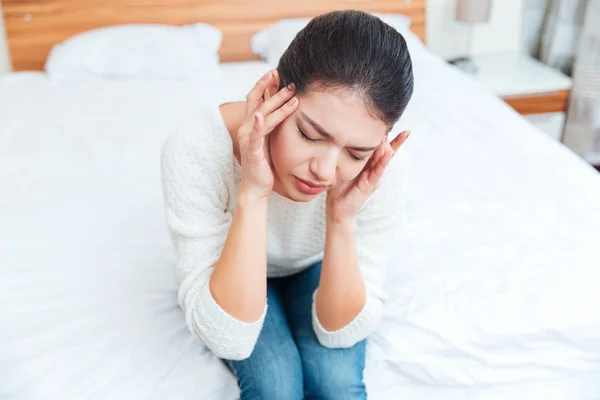 Woman sitting on the bed and having head pain