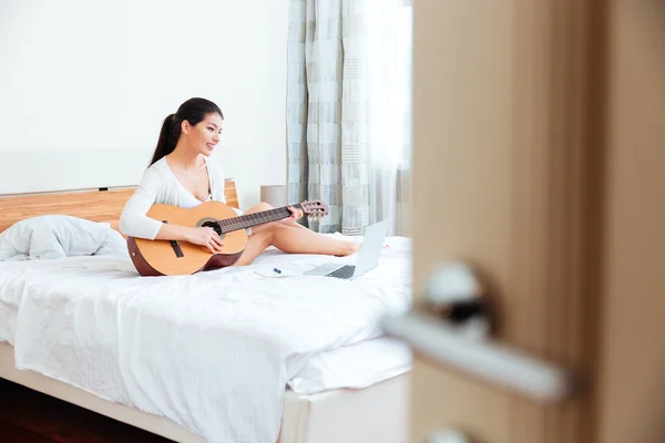 Жінка грає записи на гітарі, підтримується ноутбуком — стокове фото