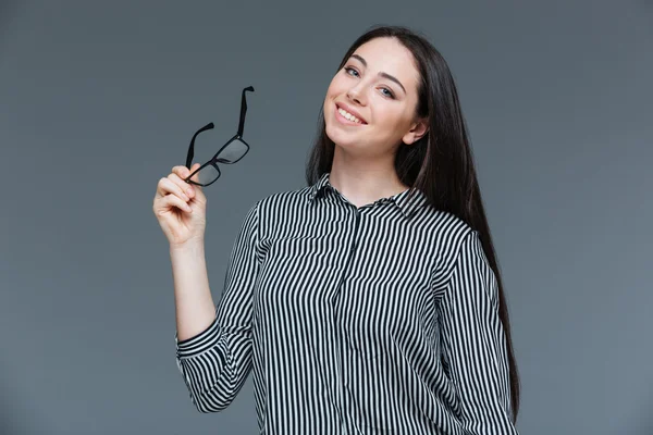 Usmívající se žena držící brýle a při pohledu na fotoaparát — Stock fotografie