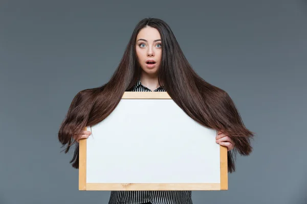 Frau mit langen Haaren hält leeres Brett — Stockfoto