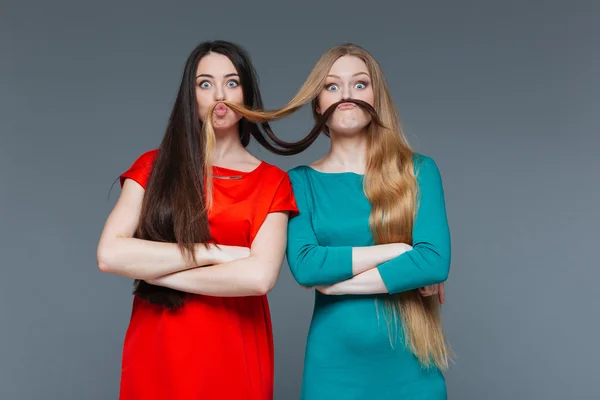 Duas garotas engraçadas fazendo bigode com seu cabelo — Fotografia de Stock