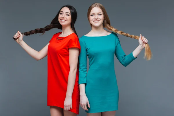 Due belle donne sorridenti in piedi e mostrando le loro lunghe trecce — Foto Stock