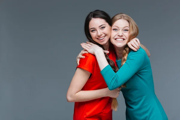 Duas mulheres jovens bonitas alegres de pé e abraçando — Fotografia de Stock