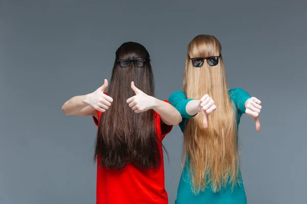 To komiske kvinder med ansigter dækket af langt hår gesturing - Stock-foto