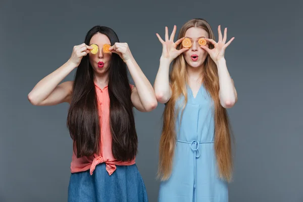 Zwei lustig staunende Frauen deckten ihre Augen mit Marmelade-Bonbons zu — Stockfoto