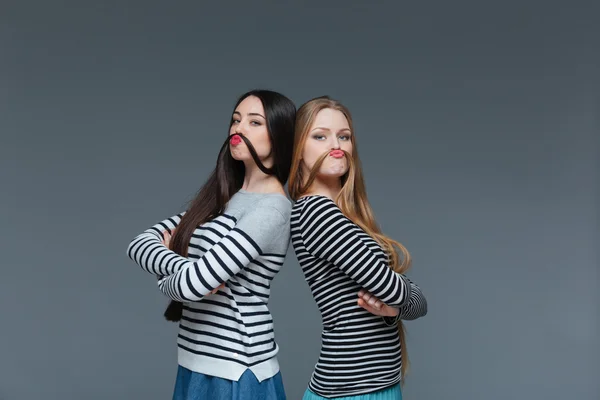 Två roliga unga kvinnor att göra mustaschen med sitt hår — Stockfoto