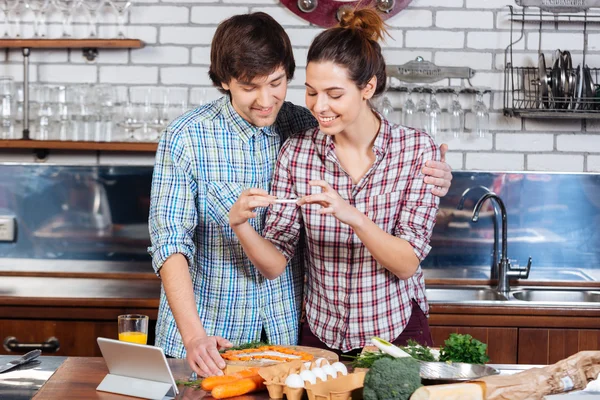 Lächelnd kochen und Fotos mit dem Smartphone in der Küche machen — Stockfoto