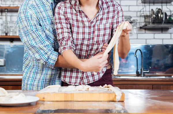 Mooie paar kneden van deeg en knuffelen op keuken — Stockfoto