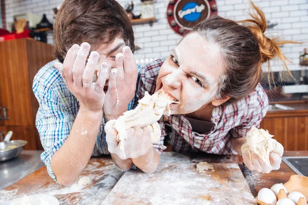 Verrücktes Paar isst ungekochten Teig und hat Spaß in der Küche — Stockfoto