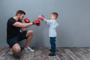 Father and little son working out in boxing gloves together clipart