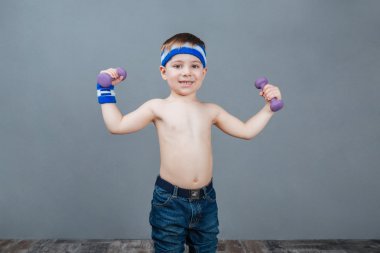 Ayakta ve dumbbells ile egzersizleri yapıyor mutlu sevimli küçük çocuk