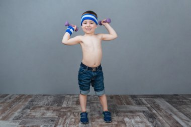 Gülümseyen küçük çocuk dumbbells ile yapıyor 