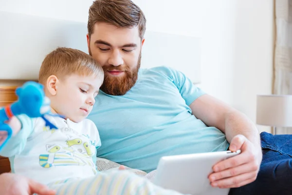 Dad and son watching catroons using tablet on bed — Stock Photo, Image