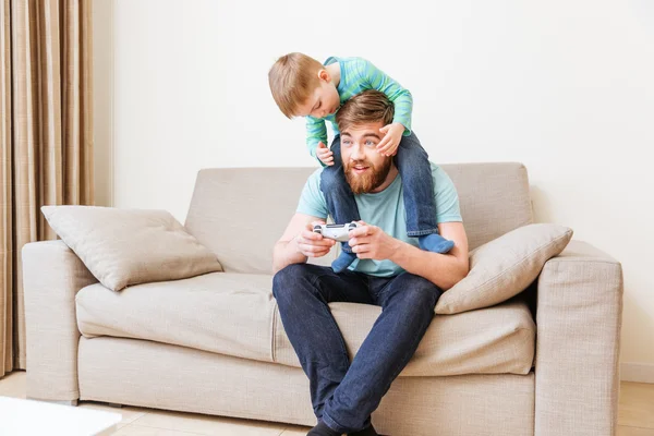 Homem feliz com seu filho nos ombros jogando jogos de computador — Fotografia de Stock