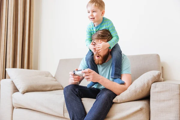 Little boy covering father eyes while he playing computer games — Stock Photo, Image