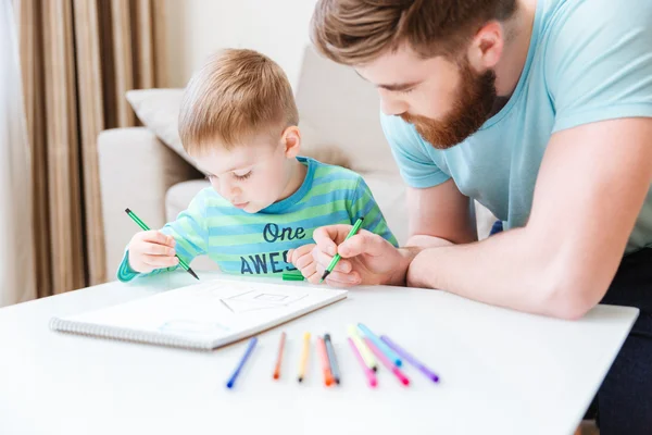 Filho e pai desenhando juntos na mesa — Fotografia de Stock