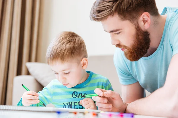 Pequeno filho e seu pai desenhando com marcadores juntos — Fotografia de Stock